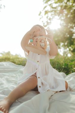 Güneşli bir parkta oynayan mutlu küçük kız. Çocukluk sevinci, Anneler Günü, açık hava aktivitesi, erken öğrenme, hayal gücü, otantik an, duygusal çocukluk, doğal ışık. Bir serinin parçası.