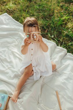 Güneşli bir parkta oynayan mutlu küçük kız. Çocukluk sevinci, Anneler Günü, açık hava aktivitesi, erken öğrenme, hayal gücü, otantik an, duygusal çocukluk, doğal ışık. Bir serinin parçası.