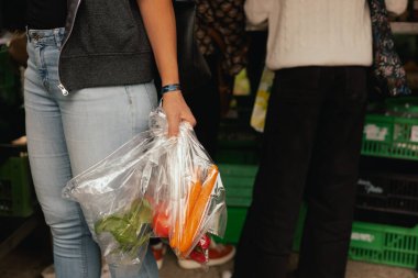 Çiftçi pazarında sebze ve yeşillikleri polietilen poşete koyup el ele tutuşun. Olgun Kadın Müşteri Dükkanı 'ndan alışveriş yapıyor. Kapatın. Dizinin bir parçası.