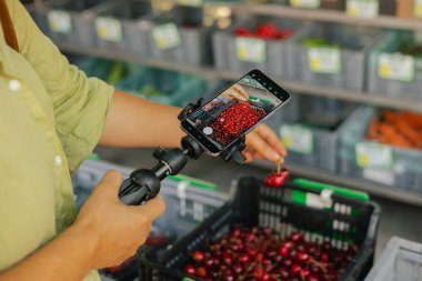 Orta yaşlı kadın blogcu çiftlik pazarında film çekiyor. Olgun Kadın Müşteri Dükkanı 'ndan alışveriş yapıyor. Sebze alan güzel bir kadın. Vlogger canlı yayın yapıyor. Kapatın. Dizinin bir parçası.