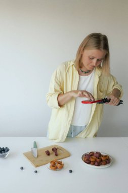 Orta yaşlı bir kadın ev yapımı meyve derisi hazırlıyor, sağlıklı bir atıştırmalık için mutfağında taze meyve dilimliyor. Organik ikramlar ve doğal yaşam üzerine bir serinin parçası. Kullanıcı tarafından oluşturulan içerik.