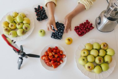 Orta yaşlı bir kadın ev yapımı meyve derisi hazırlıyor, sağlıklı bir atıştırmalık için mutfağında taze meyve dilimliyor. Organik ikramlar ve doğal yaşam üzerine bir serinin parçası. Kullanıcı tarafından oluşturulan içerik.