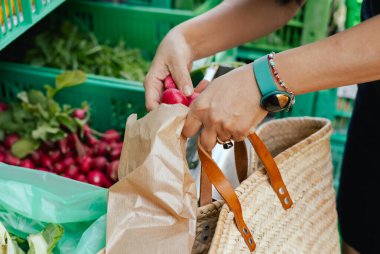 Kadın eli, markette poşete sebze koyuyor. Organik ürünler açık pazarda satılıyor. Taze ekin ve sebze hasadı satıyorum. Kapatın. Dizinin bir parçası