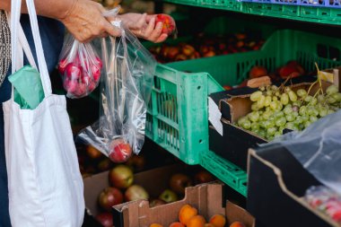 Kadın eli, markette poşete sebze koyuyor. Organik ürünler açık pazarda satılıyor. Taze ekin ve sebze hasadı satıyorum. Kapatın. Dizinin bir parçası
