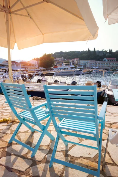コーフ島の小さなギリシャの町の湾の桟橋に木製の椅子と傘 — ストック写真