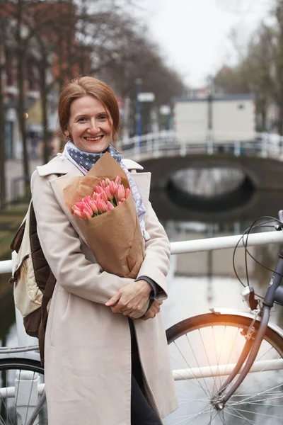 快乐的微笑的女孩拿着一束郁金香站在阿姆斯特丹的街道上 — 图库照片