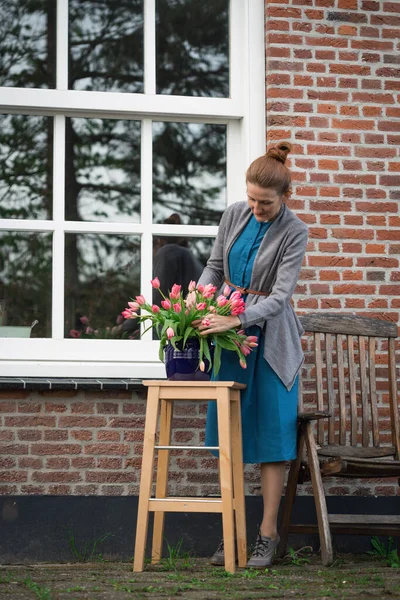 florist. girl makes a bouquet with pink tulips near with a traditional Dutch house. The Netherland