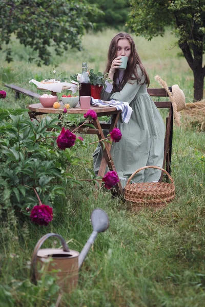 庭でお茶を飲んでいる女の子と前景には牡丹の茂み — ストック写真