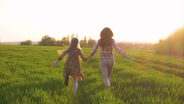 母亲和女儿在绿色的黄昏田里奔跑 — 图库视频影像