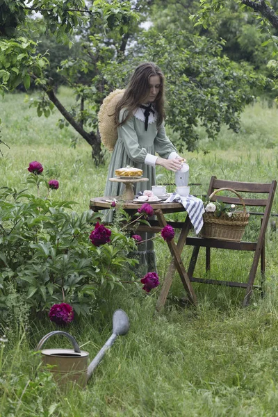 庭でお茶を飲んでいる女の子と前景には牡丹の茂み — ストック写真