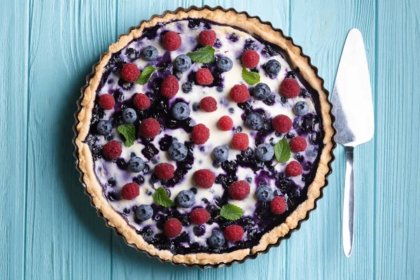 berry pie with raspberries and blueberries on a blue backgroun