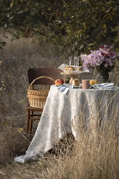 花瓶とパイのピンクの菊の美しい花束 秋の庭のテーブル上のマカロンとリンゴ まだ生きている ロイヤリティフリーのストック写真