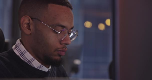 若いアフリカ系アメリカ人のビジネスマンや現代の同僚のオフィスに座って コンピュータで働く眼鏡を持つソフトウェアエンジニア 高品質の写真 — ストック動画