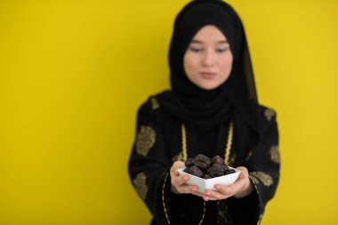 Ramazan ayının iftar saatinde elinde tatlı tarihlerle dolu bir tabak tutan modern Müslüman kadın İslami sağlıklı gıda kavramı UFO yeşil arka planda. Yüksek kalite fotoğraf