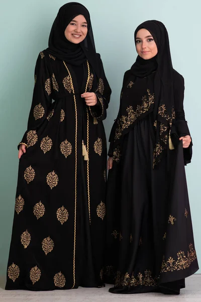 两名穿着时髦服装 被隔离在现代青色背景下的劫机者的漂亮穆斯林妇女代表了现代伊斯兰教和拉马丹 卡里姆的概念 — 图库照片
