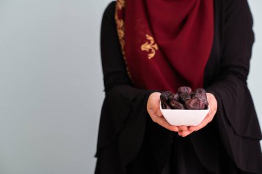 Ramon Kareem İslami sağlıklı gıda kavramında iftar zamanında elinde tatlı tarihlerle dolu bir tabak tutan modern müslüman kadın. Yüksek kalite fotoğraf