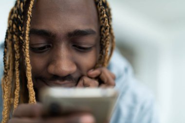 Akıllı telefon kullanan ve sosyal medyada gezinen bir afro adam. Yüksek kalite fotoğraf