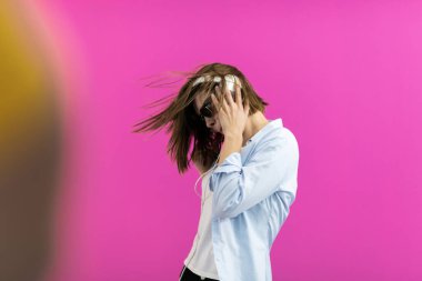Siyah gözlüklü esmer bir kadın dans ediyor ve pembe arka planda izole edilmiş müzik dinliyor. Yüksek kalite fotoğraf