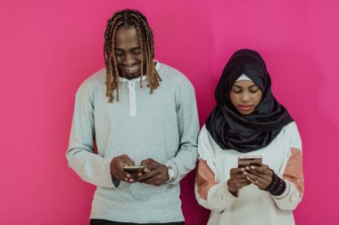 Genç Afrikalı Amerikalı çift pembe stüdyo arka planında izole edilmiş akıllı telefon uygulamaları kullanarak gülüyor. Yüksek kalite fotoğraf