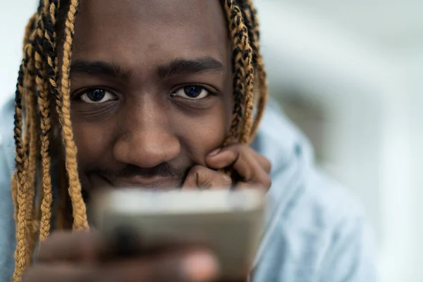 スマートフォンを使ってソーシャルメディアを閲覧しているアフロ男 高品質の写真 — ストック写真