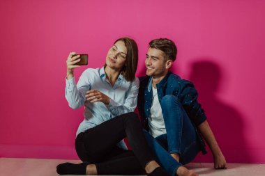 Mutlu genç bir çift evde yerde oturup selfie çekiyorlar. Yüksek kalite fotoğraf