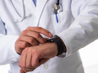 Steteskoplu doktor beyaz arka planda izole haldeyken akıllı saat kullanıyor. Yüksek kalite fotoğraf