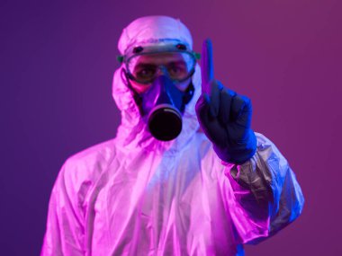 Coronavirus covid-19 salgını. Küresel sağlık salgını uyarısı ve mavi ve pembe neon ışıklı arka plandaki tehlike nedeniyle koruyucu biyolojik kıyafet ve maske giyen doktor.