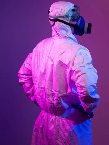 コロナウイルスCovid 19パンデミック 世界的なヘルスケアの流行による保護生物学的スーツとマスクを身に着けている医師科学者警告と青とピンクのネオンライトの背景の危険性 — ストック写真
