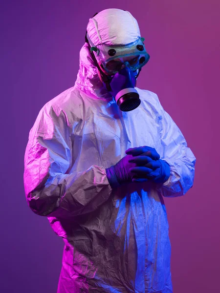 Coronavirus covid-19 pandemic. Doctor scientist wearing protective biological suit and mask due to global healthcare epidemic warning and danger background in blue and pink neon lights background