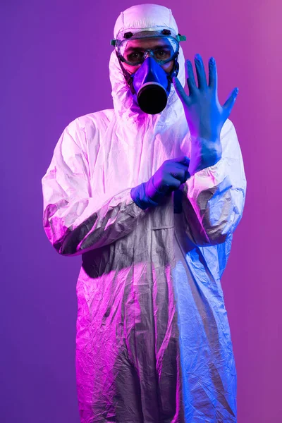 コロナウイルスCovid 19パンデミック 世界的なヘルスケアの流行による保護生物学的スーツとマスクを身に着けている医師科学者警告と青とピンクのネオンライトの背景の危険性 — ストック写真