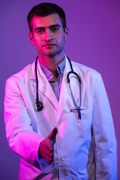 一个穿着白衣的英雄的画像 带着听诊器的快乐微笑的年轻医生站在医院的蓝色和粉色背景上 警告科罗纳维病毒Covid 19的危险 — 图库照片