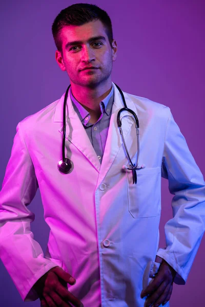 科罗纳维尤斯Covid 19危险警报白衣英雄的肖像 带着听诊器的快乐微笑的年轻医生站在蓝色和粉色的背景下 高质量的照片 — 图库照片
