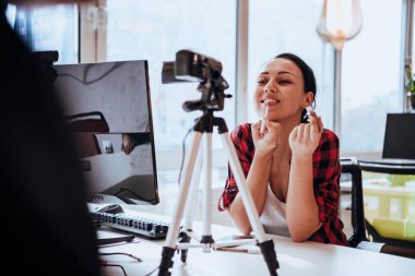 İş yerini online müşterilere sunmak için kamera kullanan genç bir kadın..