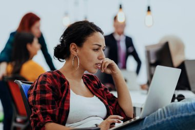 Modern ofiste laptopla çalışan mutlu bir kadın. Etrafında arkadaşları var.. 