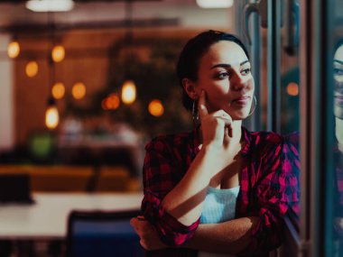 Geceleri ofiste pencerenin yanındaki modern bir kadının portresi. Yüksek kalite fotoğraf