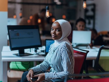 İş eğitimi ve ofis konsepti. Afrikalı Amerikalı iş kadını tesettür takıyor, çalışıyor, bilgisayarda daktilo yazıyor. Masasında oturan bir girişimci kadın var. Yüksek kalite fotoğraf