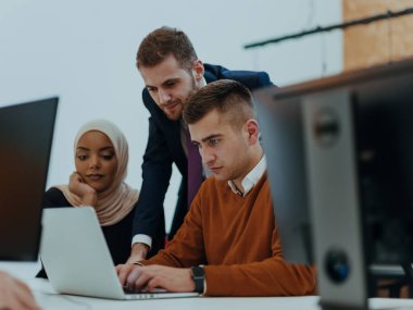 Masaüstü bilgisayarlar, dizüstü bilgisayarlar üzerinde çalışan ve fikirlerini modern bir ofis alanında paylaşan çok ırklı çalışma arkadaşları. Genç nüfuzlu kişiler çevrimiçi pazarlama projeleri üzerinde çalışıyorlar