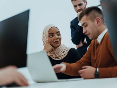 Masaüstü bilgisayarlar, dizüstü bilgisayarlar üzerinde çalışan ve fikirlerini modern bir ofis alanında paylaşan çok ırklı çalışma arkadaşları. Genç nüfuzlu kişiler çevrimiçi pazarlama projeleri üzerinde çalışıyorlar