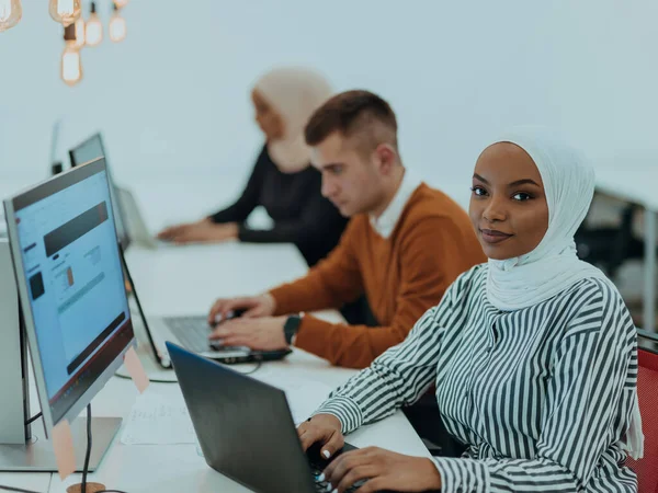 Group of multi-ethnic colleagues working on desktop computers, laptops and sharing their ideas in a modern office space. Young influencers work on online marketing projects