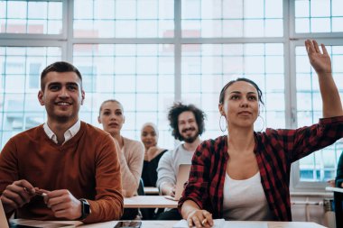 Çeşitli erkek ve kadınlardan oluşan bir grup modern bir sınıfta oturup iş eğitimi hakkında bir konferans dinliyorlar. Yüksek kalite fotoğraf