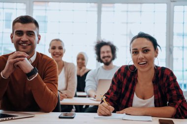 Çeşitli erkek ve kadınlardan oluşan bir grup modern bir sınıfta oturup iş eğitimi hakkında bir konferans dinliyorlar. Yüksek kalite fotoğraf