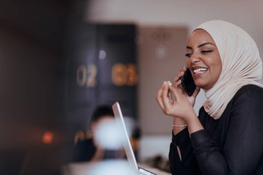 Genç Afrikalı Amerikalı iş kadını modern bir ofiste akıllı bir telefonla konuşuyor. Pazarlama konsepti. Çok ırklı toplum. 