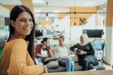 Kadın patron, yönetici yönetici. Etrafı iş arkadaşlarıyla çevriliyken modern bir ofiste poz veriyor.