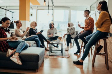 Genç tasarımcı, konferans odasındaki ortaklarına proje hakkında yeni fikirler veriyor. İşadamları yeni iş projelerini tartışıyorlar.