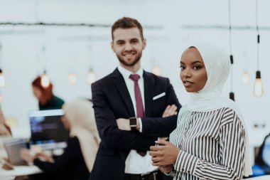 Modern bir ofiste ekibiyle poz veren resmi bir iş adamı ve Afrikalı genç bir iş kadınının portresi. Pazarlama konsepti. Çok ırklı toplum