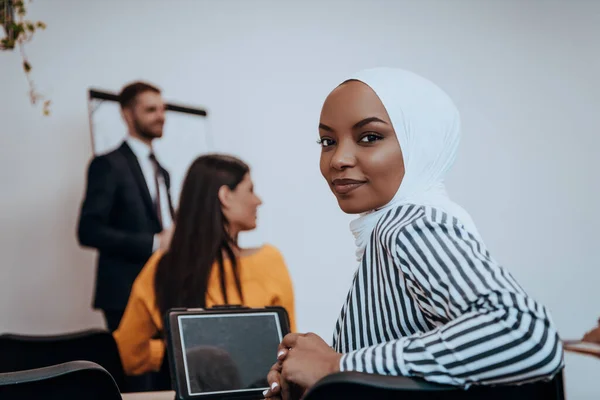 African American Muslim woman listens to a lecture aimed at business training.