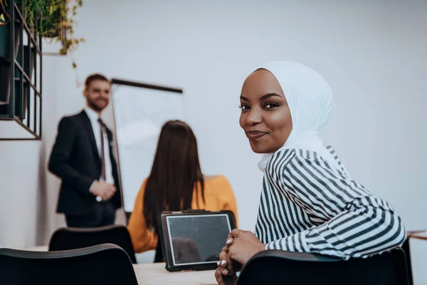African American Muslim woman listens to a lecture aimed at business training.