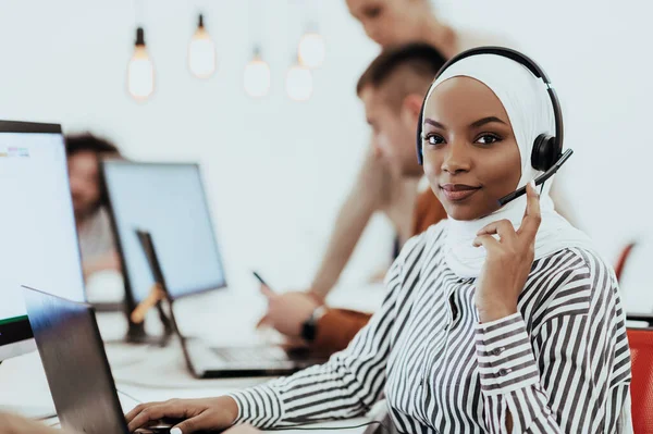 stock image African American Muslim woman with hijab and headset working as customer support in a modern office