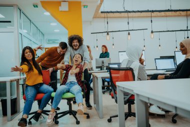 Takım oluşturma ve ofis eğlencesi. Şık giyinen neşeli iş adamları ofis sandalyelerinde yarışırken eğleniyorlar ve gülümsüyorlar.