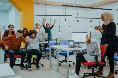 Takım oluşturma ve ofis eğlencesi. Şık giyinen neşeli iş adamları ofis sandalyelerinde yarışırken eğleniyorlar ve gülümsüyorlar.